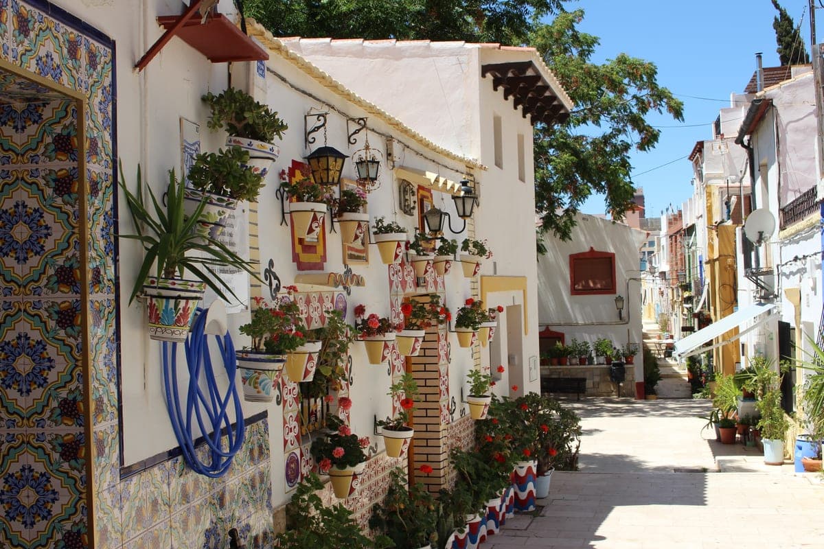 Stradă albă din Barrio de Santa Cruz, cu ghivece cu flori și faianță.