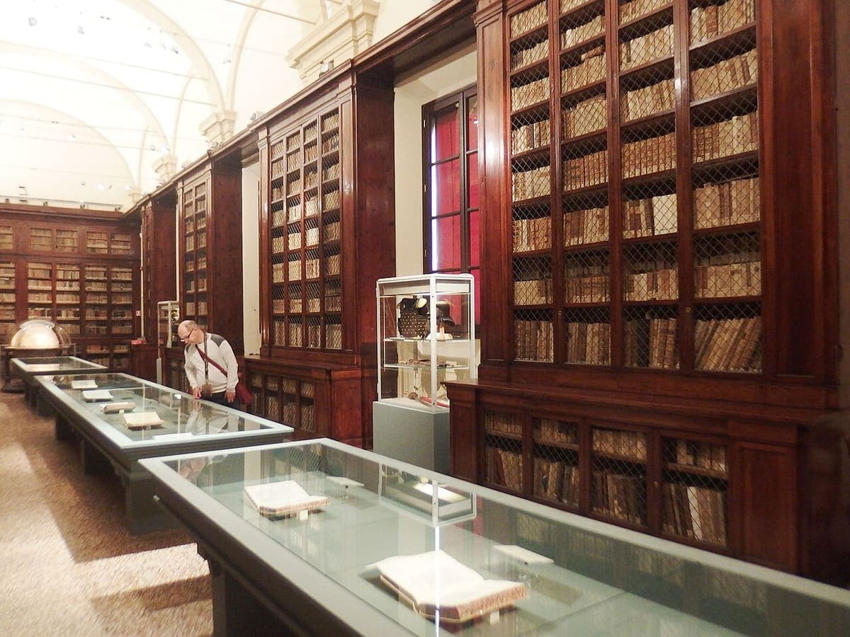 Sala-bibliotecă din Palazzo Poggi, cu rafturi de lemn până în tavan și vitrine cu cărți vechi.