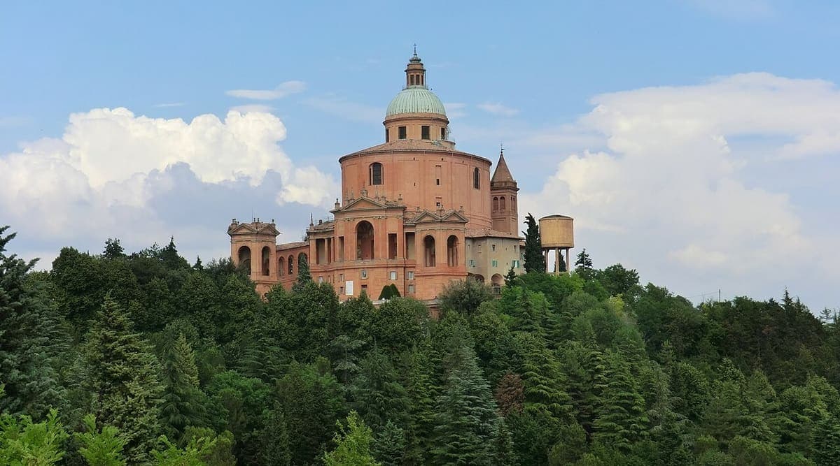 Sanctuarul Madonna di San Luca, cu cupola lui, deasupra pădurii de pe deal.