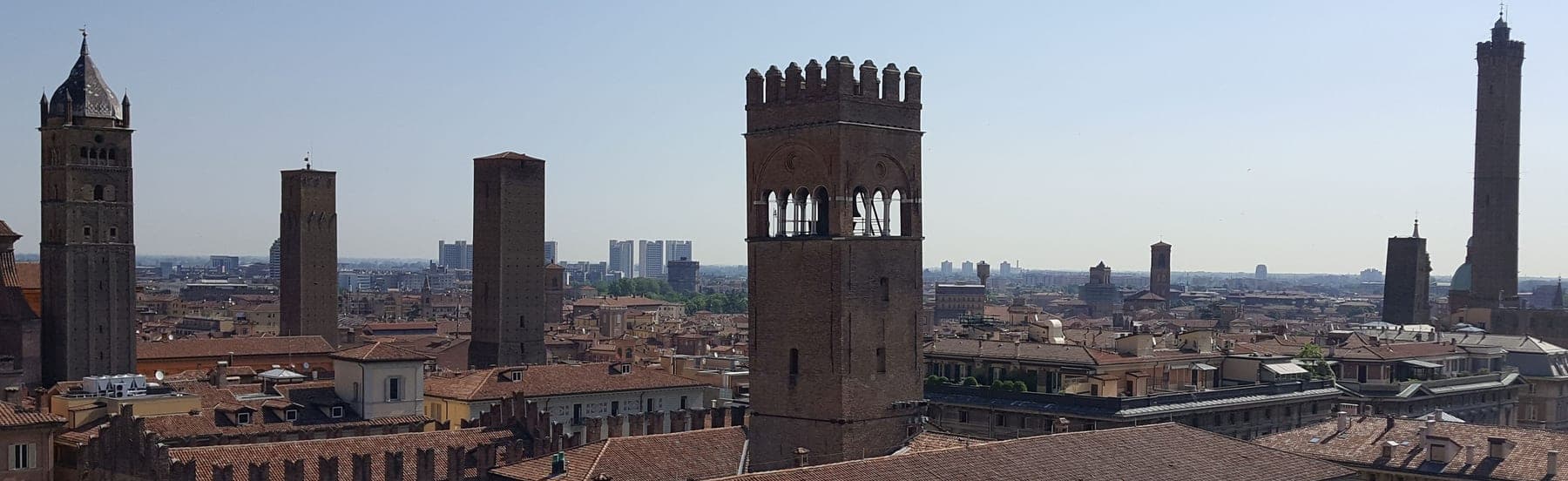 Turnurile Asinelli și Garisenda văzute de sus, peste acoperișurile roșii ale Bolognei, de pe terasa Turnului cu Ceas.