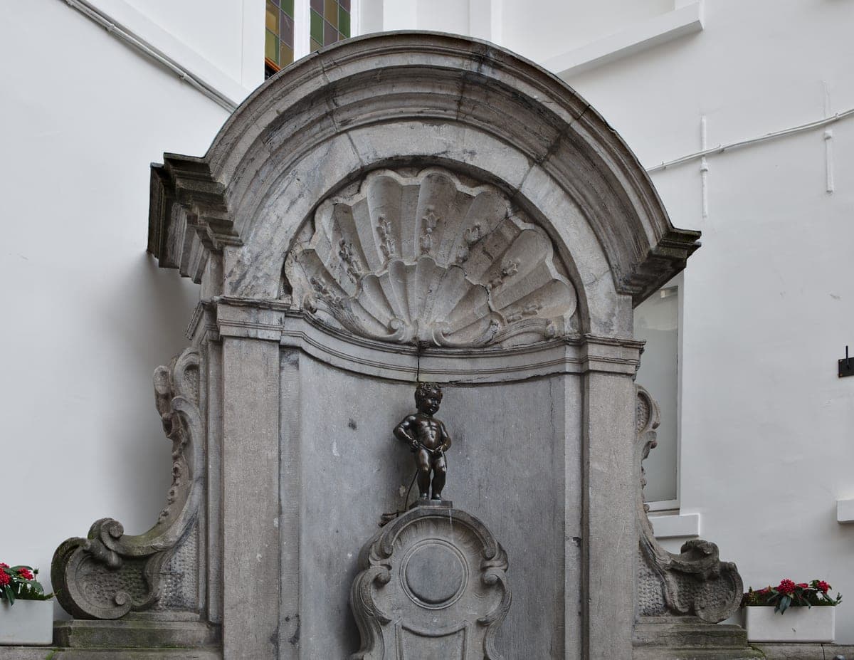 Statuia Manneken Pis în nişa de piatră a fântânii.