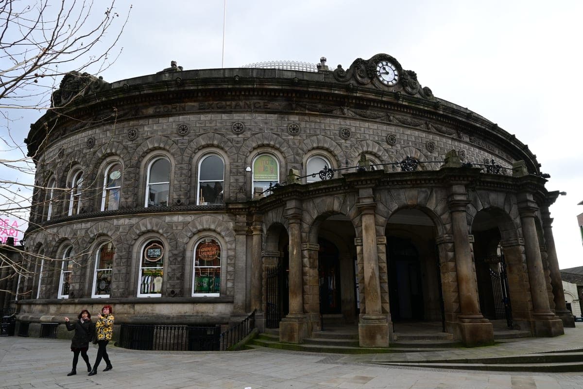 Clădirea rotundă a Leeds Corn Exchange, cu arcade și ceas deasupra intrării.