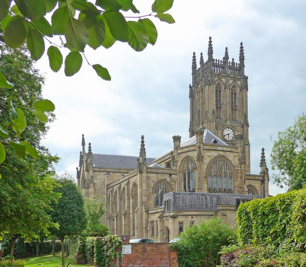 Leeds Minster, cu turnul cu ceas, văzut printre copaci.