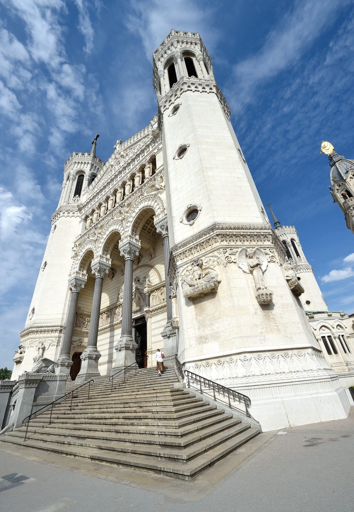 Fațada albă a bazilicii Notre-Dame de Fourvière, cu treptele din față.