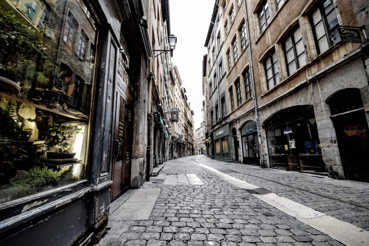 Stradă pietruită din Vieux Lyon, cu fațade vechi și vitrine.