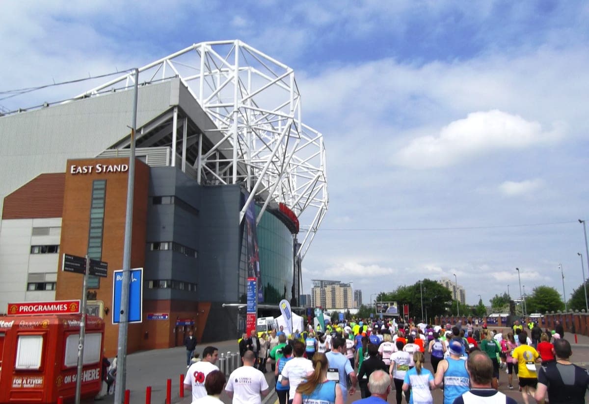 Tribuna East Stand de la Old Trafford, cu arcadele albe de deasupra, într-o zi însorită.