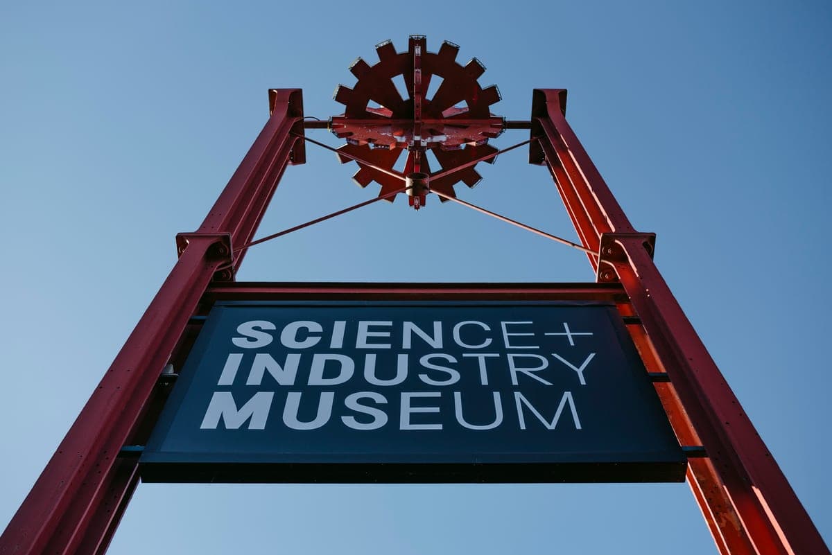 Firma de la intrarea în Science and Industry Museum, pe un stâlp roșu, sub cerul senin.