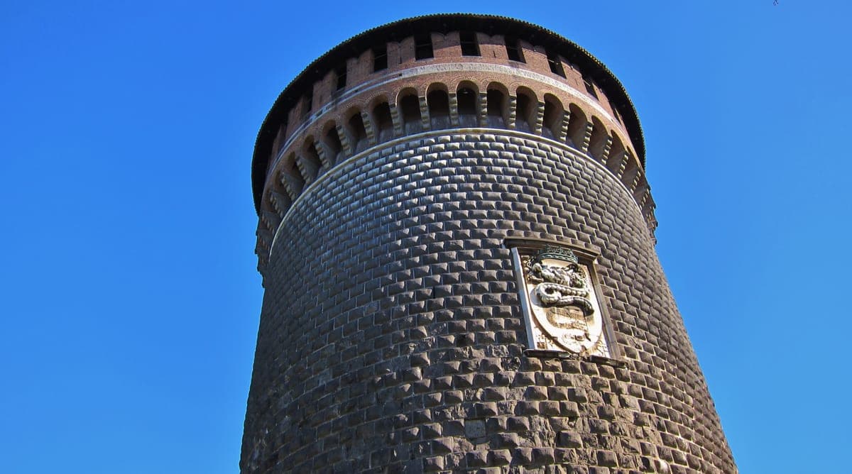 Turnul rotund al Castelului Sforzesco, cu stema familiei Sforza, deasupra zidului de cărămidă.