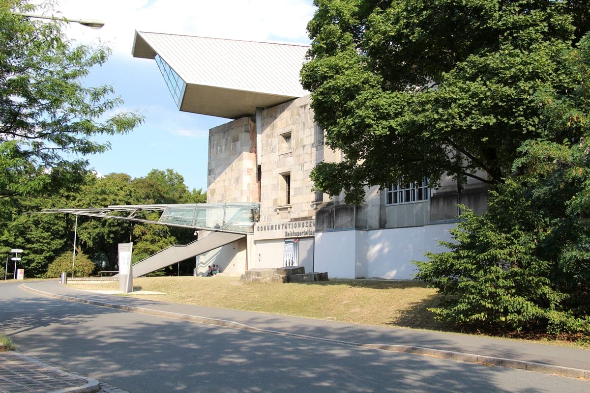Intrarea Dokumentationszentrum, cu pasarela de sticlă și acoperișul în consolă.