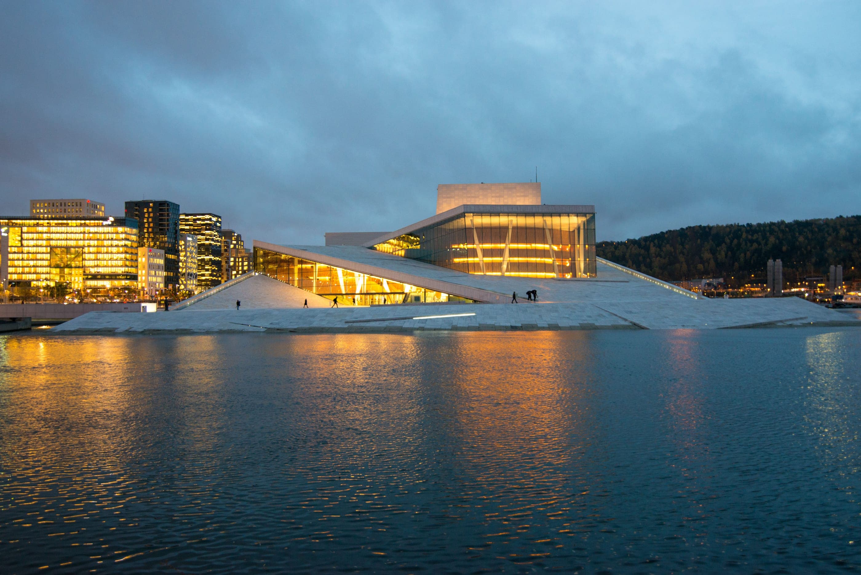 Opera din Oslo la lăsarea serii, cu acoperișul ei alb coborând spre apele fiordului.