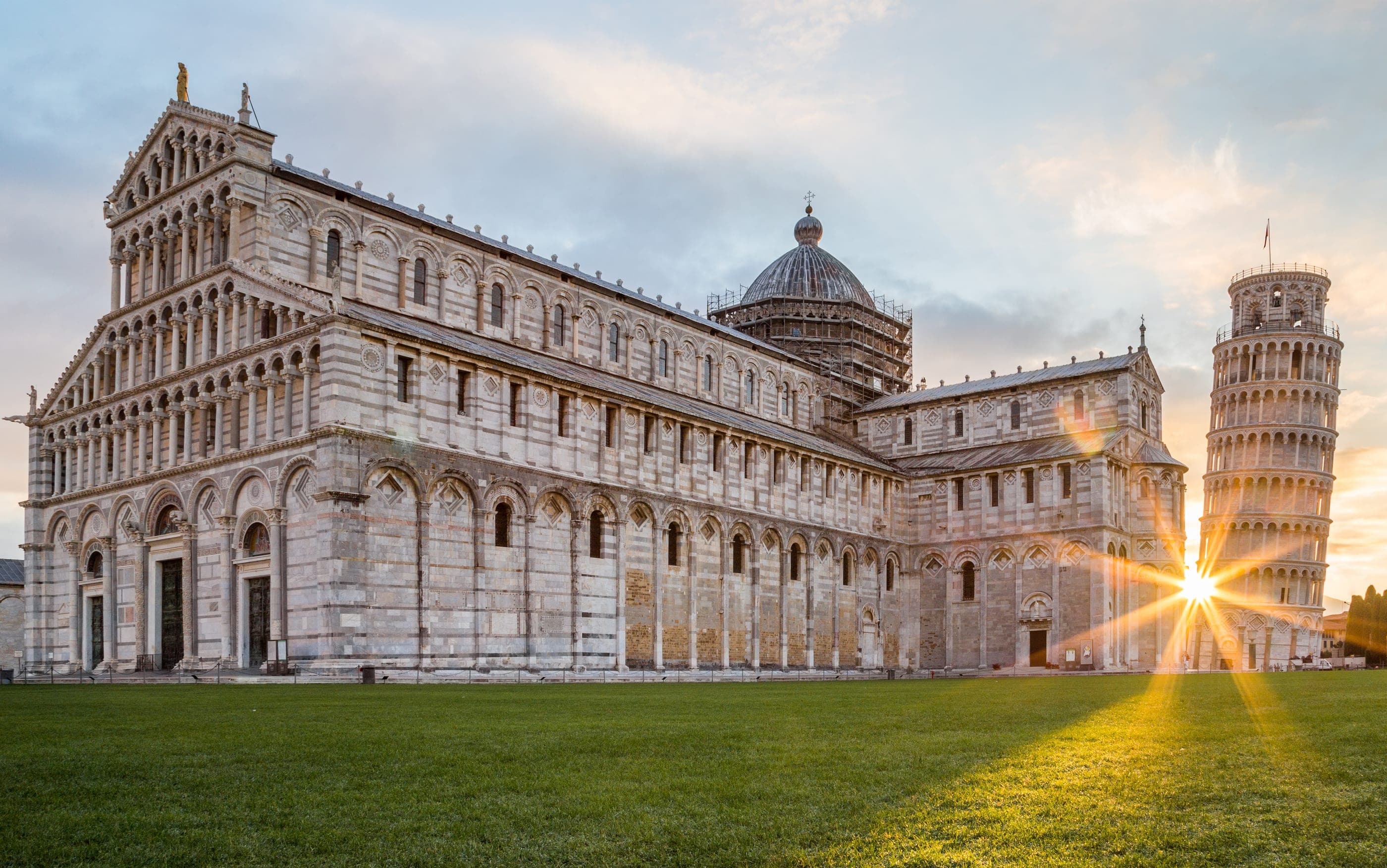 Catedrala și Turnul înclinat din Pisa la răsărit, văzute de pe gazonul din Piazza dei Miracoli.