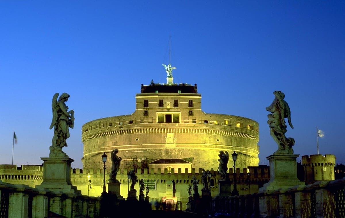 Castel Sant'Angelo luminat în amurg, văzut de pe podul cu statuile de îngeri.