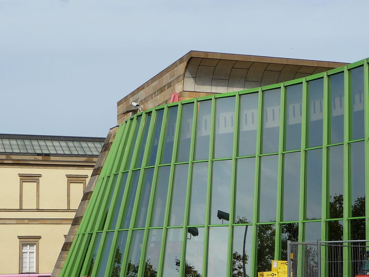 Fațada verde, curbată, a Neue Staatsgalerie, lângă clădirea veche a muzeului.